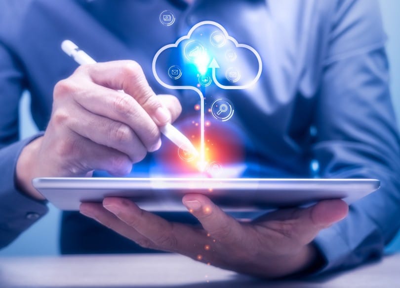 small business cybersecurity through the cloud - man holding tablet with cloud symbol above